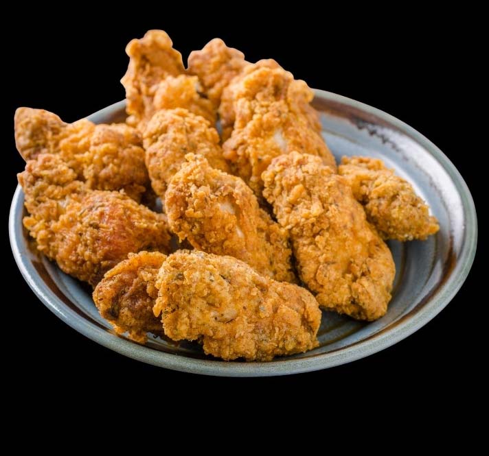 A gray plate with crispy fried chicken at Fifth Avenue Taphouse New Brighton, against a black background.