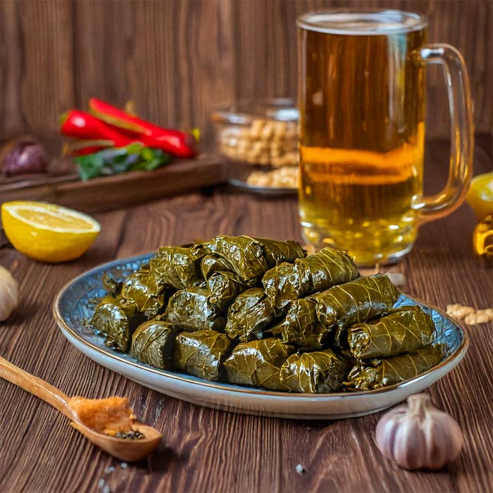 A plate of stuffed grape leaves at Fifth Avenue Taphouse New Brighton with beer and garnishes.