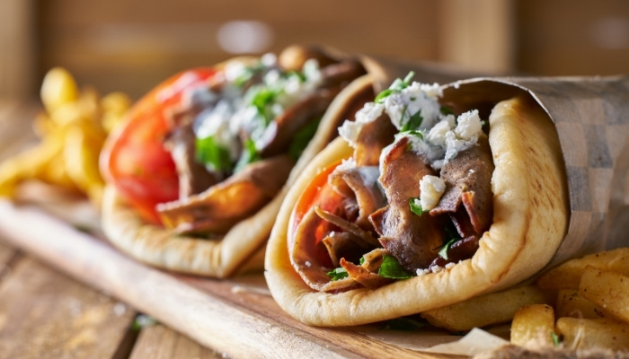 Two gyros in pita with veggies, meat, and cheese, served with fries at New Brighton Restaurant.
