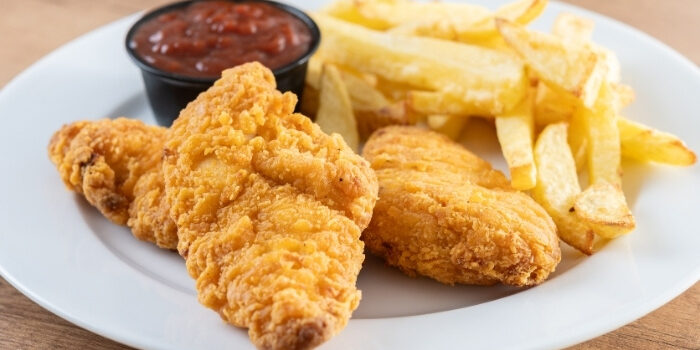 Fried chicken tenders and fries served fresh at New Brighton Bar on a white plate.