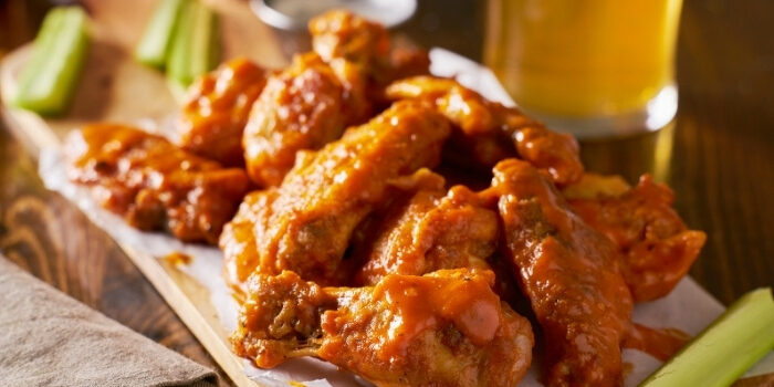Buffalo chicken wings at Fifth Avenue Taphouse New Brighton, served with celery and a drink.