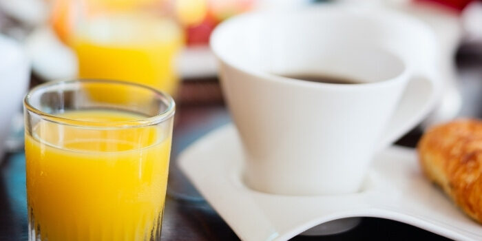 A glass of orange juice, coffee, and a croissant at New Brighton Restaurant on a table.