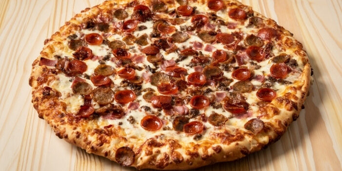 A large cooked pizza with pepperoni, sausage, and bacon at Fifth Avenue Taphouse New Brighton.